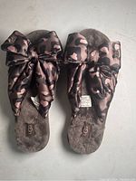 Pair of Ugg slides with soft brown fur lining and leopard-print bows from a top angle.