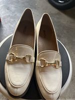 Top-down view of cream leather men's loafers showing gold-tone horsebit detail and insole branding