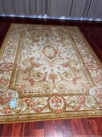 Full view of the 8x6 feet area rug showing the overall pattern and colors of cream, orange, and green.