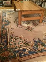 Close-up of the edge and corner showing the floral pattern and texture of the wool rug.