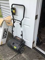 Full view of Yardworks electric dethatcher with handle upright, showing control switch and body.