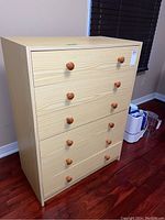 Full front view showing six drawers and wood grain pattern on a wooden dresser.