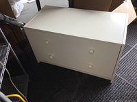 Front and top angled view of the white 2-drawer dresser showing overall condition and design.