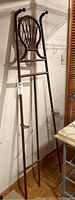 Full height view of the wooden standing easel leaning against a wall, showing the overall structure and the backrest design.