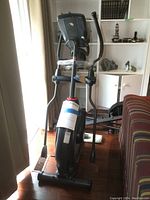 Full front view of elliptical machine showing frame, flywheel housing, and handlebars