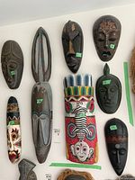 Overview photo showing all eight carved wood masks arranged on a wall with varied sizes and styles