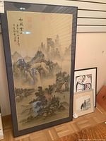 Frontal photo of the large framed watercolor painting showing the full Asian mountain landscape scene with calligraphy and stamps.