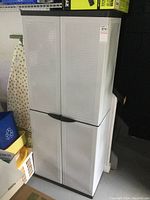 Full front and partial side view of the white resin 2 door cabinet in garage environment.