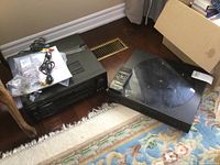 Wide shot showing Pioneer receiver, Technics CD player, remotes, and cables on floor next to rug and wooden flooring.