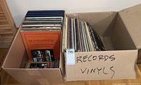 Photo of two cardboard boxes labeled 'RECORDS VINYL', filled with vinyl records and PC video game boxes visible at bottom