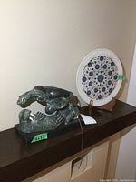 Side view showing Inuit wolf and walrus stone sculpture on rectangular base with decorative marble plate behind