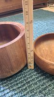 Two wooden bowls on a carpet, ruler measuring the height of the deeper bowl at about 7 inches tall