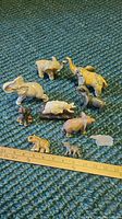 Photo showing all 10 elephant figurines arranged on a textured blue surface with a ruler for scale.