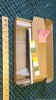Clear acrylic computer screen organizer in open cardboard box, measuring approximately 16.5 inches long shown next to wooden ruler
