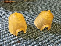 Two frosted glass slip shades with Art Deco pattern, each with top finial and cutout base for fixture attachment, shown on a woven textile surface.