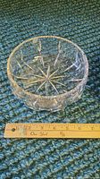 Small clear cut glass bowl with starburst pattern bottom shown beside a ruler for scale.