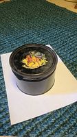 View of the closed round vintage coffee tin with colorful cowboy illustration on the lid.