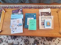 Top-down photo showing all books arranged on wooden table including titles on silver, glass, furniture, pewter.