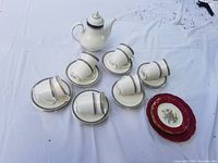 Overview of all pieces including Royal Doulton coffee pot, six matching cups and saucers, plus Limoges dessert plates.