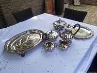 Photo showing all silver plate pieces including tea service and platter on table