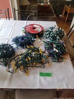 Six strings of Noma outdoor Christmas lights arranged on table showing variety of colors and bulb styles.