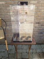 Front view of the clear plexiglass display case showing locking door with missing key and black base.