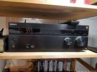Front view of Sony receiver on wooden shelf with power and control knobs visible
