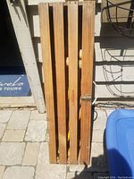 Closed wooden slatted box showing four slats and latch, box handle on top, contains croquet set items inside.