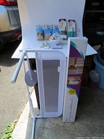 Overview of white mesh stair gate, boxed stairway gate installation kit, and other baby safety accessories on display table.