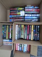 Top view of three boxes of books, showing a variety of book spines with different authors and titles visible.