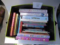 Top view of large box filled with various used children's books and two large canvas art kits at the bottom