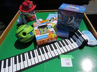 Photo of foldable piano keyboard, green ball, Paw Patrol Marshall robot, Namco Classic game system, and Disney Princess toy box arranged on tray