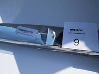 Rolled clear plastic tablecloth with barcode label inside damaged packaging, placed on a white surface.