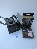 Huawei Watch GT 2 smartwatch in open box with charging cable, black band shown. Two brand new pairs of wireless earbuds are in original packaging (Escape TWS in black and iCnects ICT6 in pink).