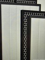 Close-up of two rectangular replacement air filters with black frames and white pleated filter surfaces featuring metallic honeycomb mesh overlay.