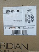 Close-up photo of the product label on the box showing Meridian Lighting, model M10001-176, silver lace finish, with a sketch of the chandelier design.