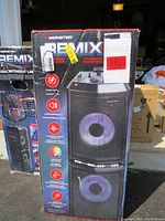 Damaged original packaging box showing Monster REMIX branding, speaker, and listing key features like 300 watts power, dual 10" subwoofers, and multi-color lights.