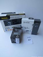 Photo showing boxed Sound Storm Labs ML46DB car receiver, boxed Focal Sphear earphones, and boxed ZOKO wireless device on a table with a lot number card.