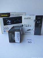 Photo showing boxed SSL ML46DB car receiver, Focal Sphear S earphones box, and ZOKO speaker packaging clustered together.