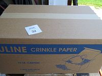 Closed cardboard box labeled 'Uline Crinkle Paper' with blue graphics and text indicating 10 lb carton weight.