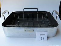 Front angled view of the VE Chef roasting pan showing the rectangular black interior and polished silver-tone exterior with attached metal handles and removable roasting cage inside.