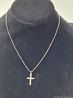 Cross pendant displayed on a black bust form showing the overall look and length of the chain.