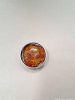Top view of amber pendant showing amber stone with natural inclusions in sterling silver bezel setting.