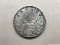 Obverse side of the 1961 Canada silver dollar coin showing two figures in a canoe with date and inscriptions.