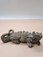 Full side view of the concrete dragon ornament showcasing body and curled tail.