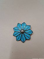 Front view of the brooch showing blue enamel petals and silver center detail.