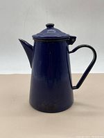 Side view of blue enameled steel pitcher with lid, showing its conical shape, handle and spout.