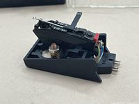 Side angle showing black cartridge part with attached wires and needle arm.