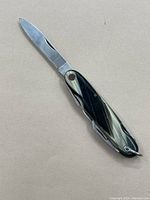 Photo of folding pocket knife with blade extended, showing handle pattern and overall shape.