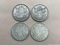 Top view of four Canadian 50 cent coins arranged on a flat surface, showing details of the coat of arms and year.